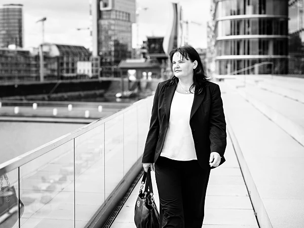 Frau im Business-Outfit auf moderner Promenade, Blick zur Seite