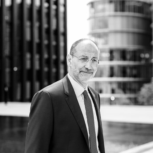 Man in suit in front of round glass architecture, looking directly into the camera