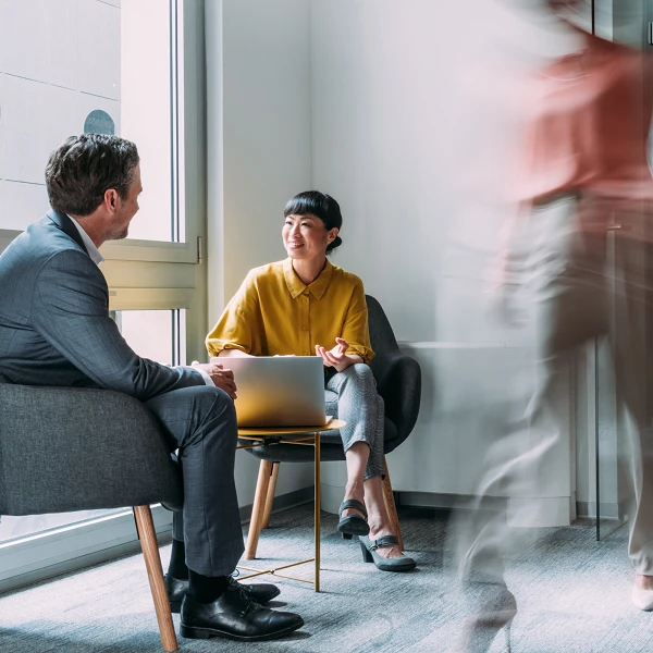 Two people talking at a laptop, modern office scene with motion blur