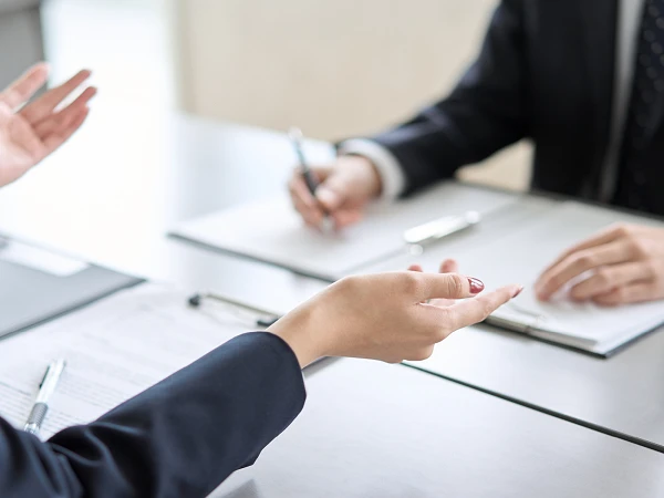 Conversation scene between two people at a table with documents and pen in hand